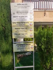 שלט מרפאת ד"ר גיא וולפין עם רשימת הרופאים המומחים ופרטי יצירת קשר