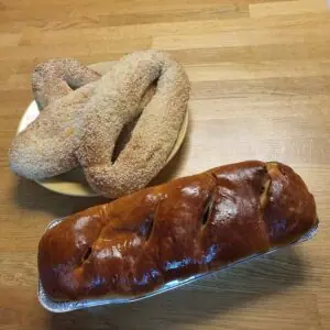 כעכי שומשום וכיכר חלה מוזהבת מונחים על שולחן עץ